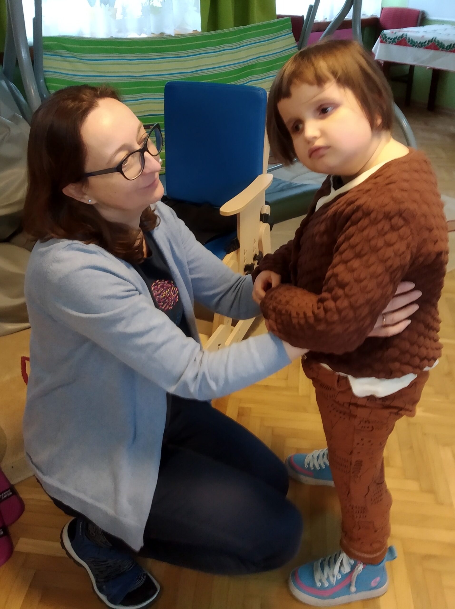 Lilianka wspierana przez panią Agnieszkę stojąc, wsłuchuje się w dźwięki ludowej muzyki