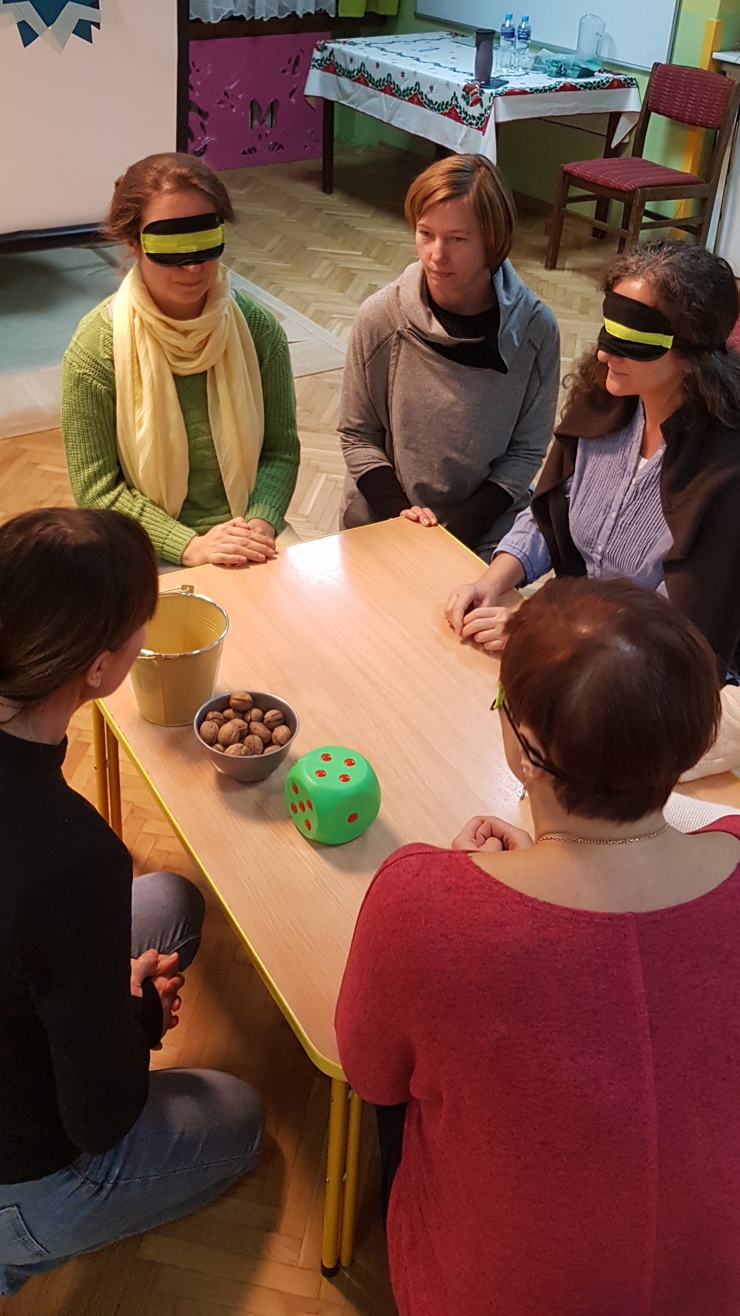 Grupa nauczycieli w opaskach na oczach i bez opasek siedzą przy małym stoliku