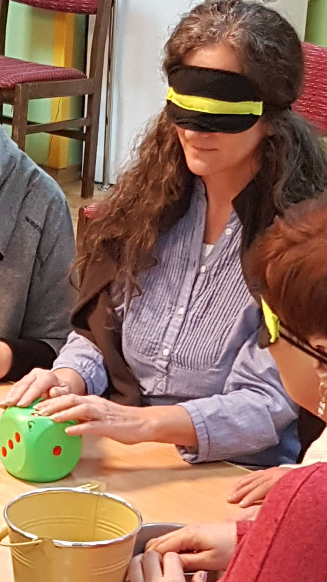 Pani Ania w opasce na oczach ogla da palcami dużą kostkę do gry.