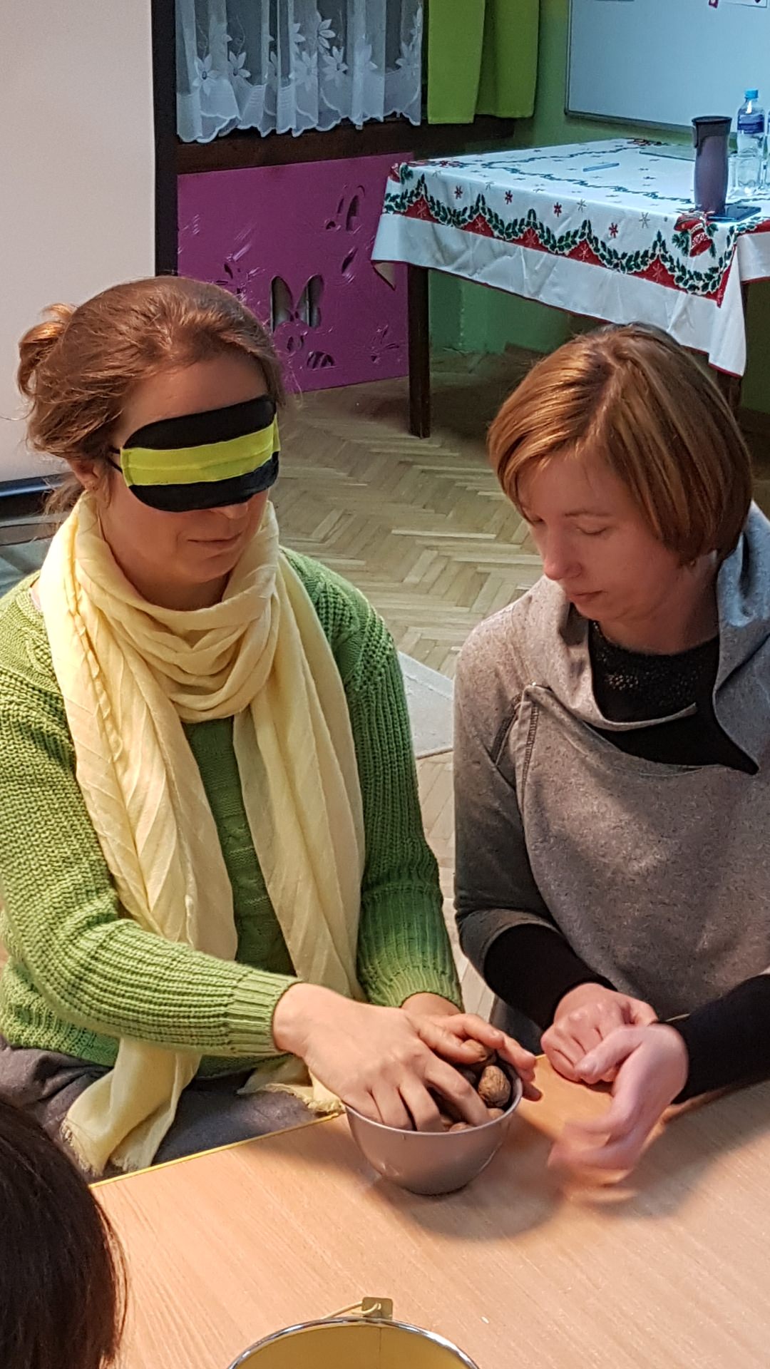 Pani Monika asystuje Pani Beacie, ktor a w opasce na oczach ogląda orzechy