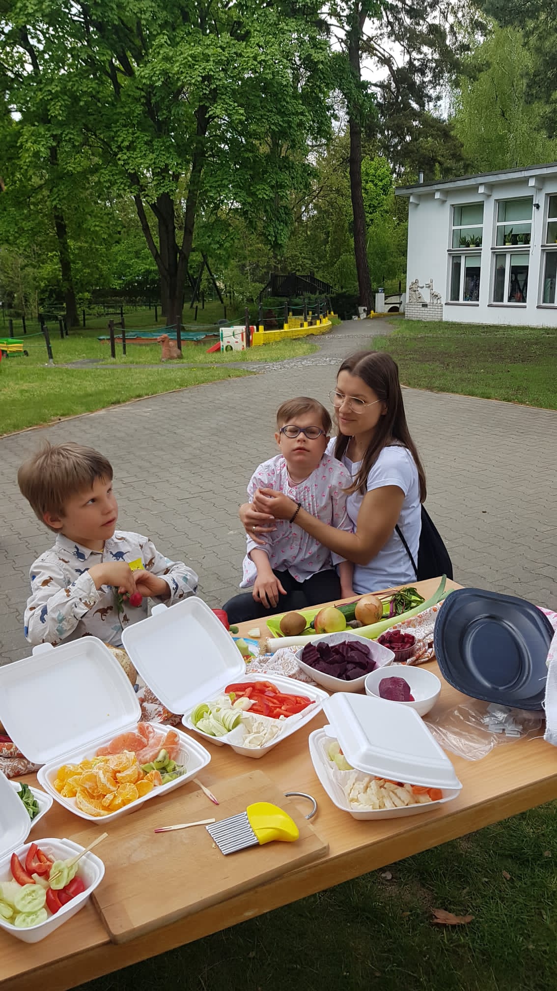 Chłopcy jedzą przygotowane warzywa i owoce.