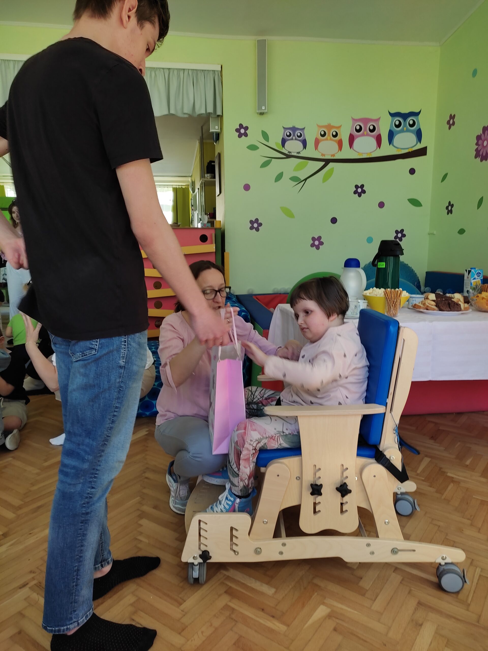 Jeden z uczniów liceum wręcza prezent dziewczynce na wózku.