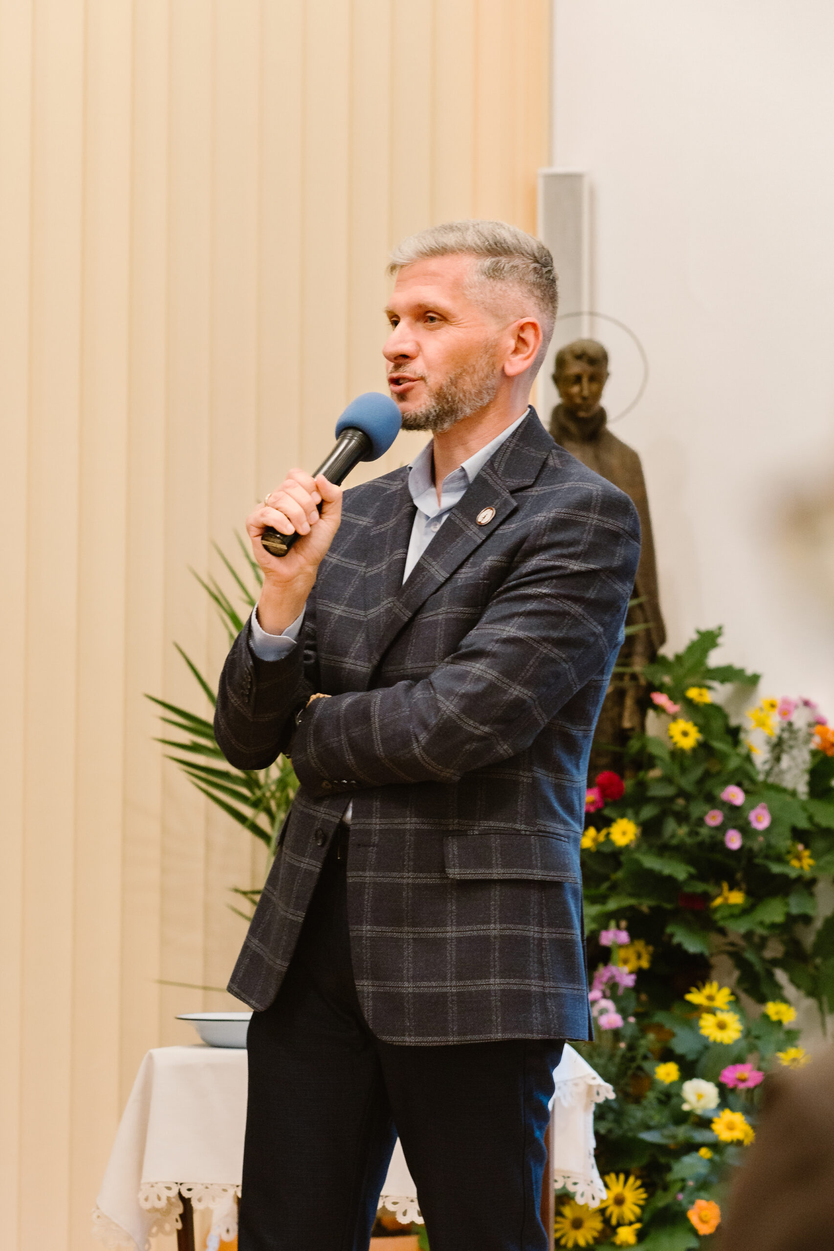 Paweł Kacprzyk trzyma mikrofon.