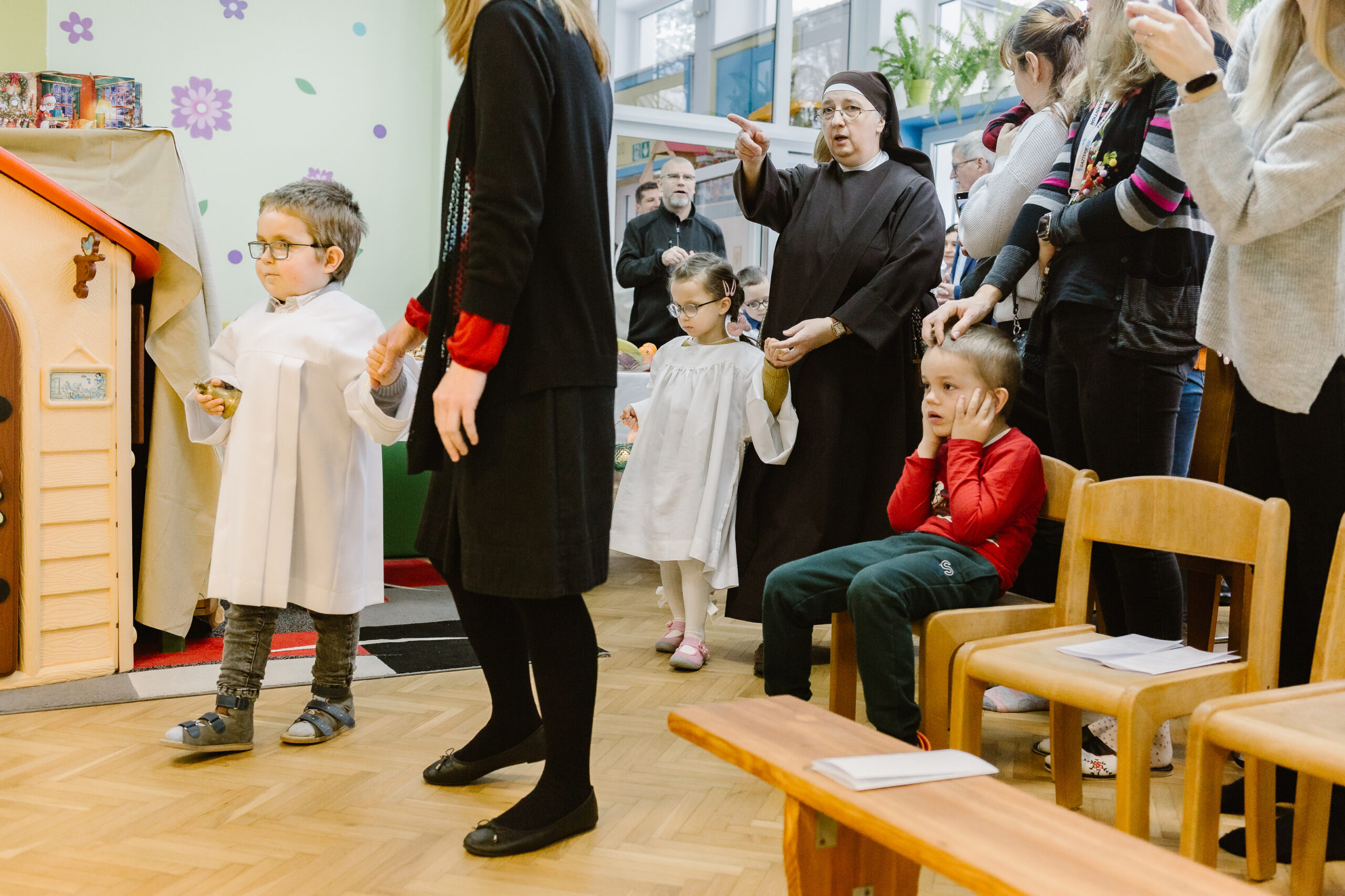 Przedszkolaki niosą lampiony w procesji.