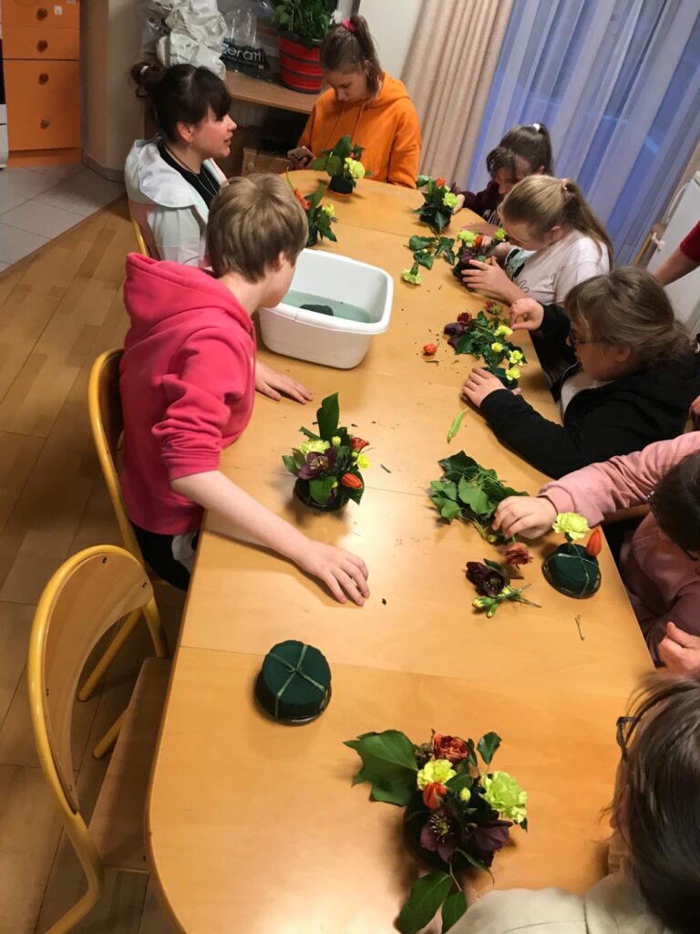 Dziewczęta układają  kompozycje kwiatowe