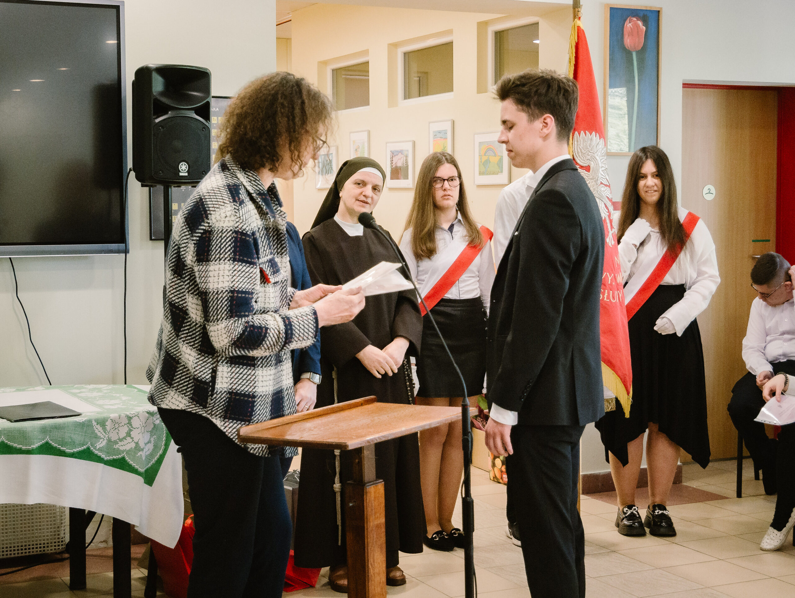 Wychowawczyni klasy licealnej wręcza świadectwo jednemu z uczniów.