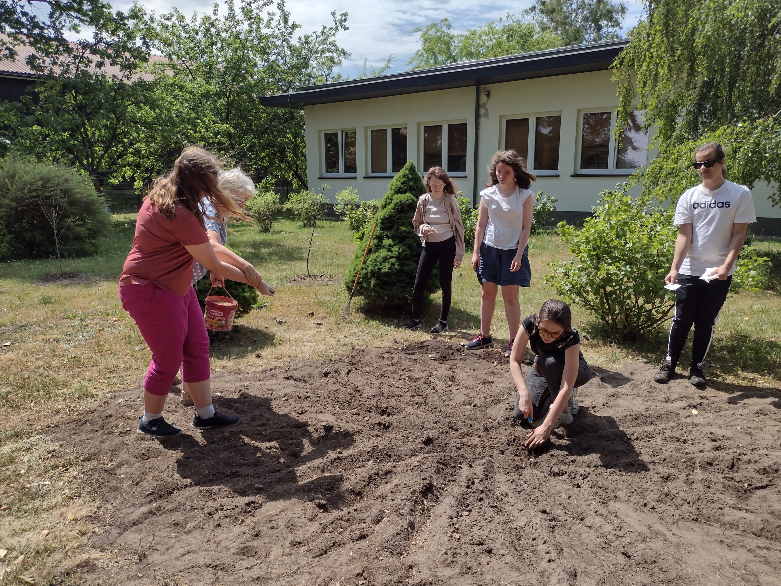 Uczniowie sieją ziarna kwiatów.