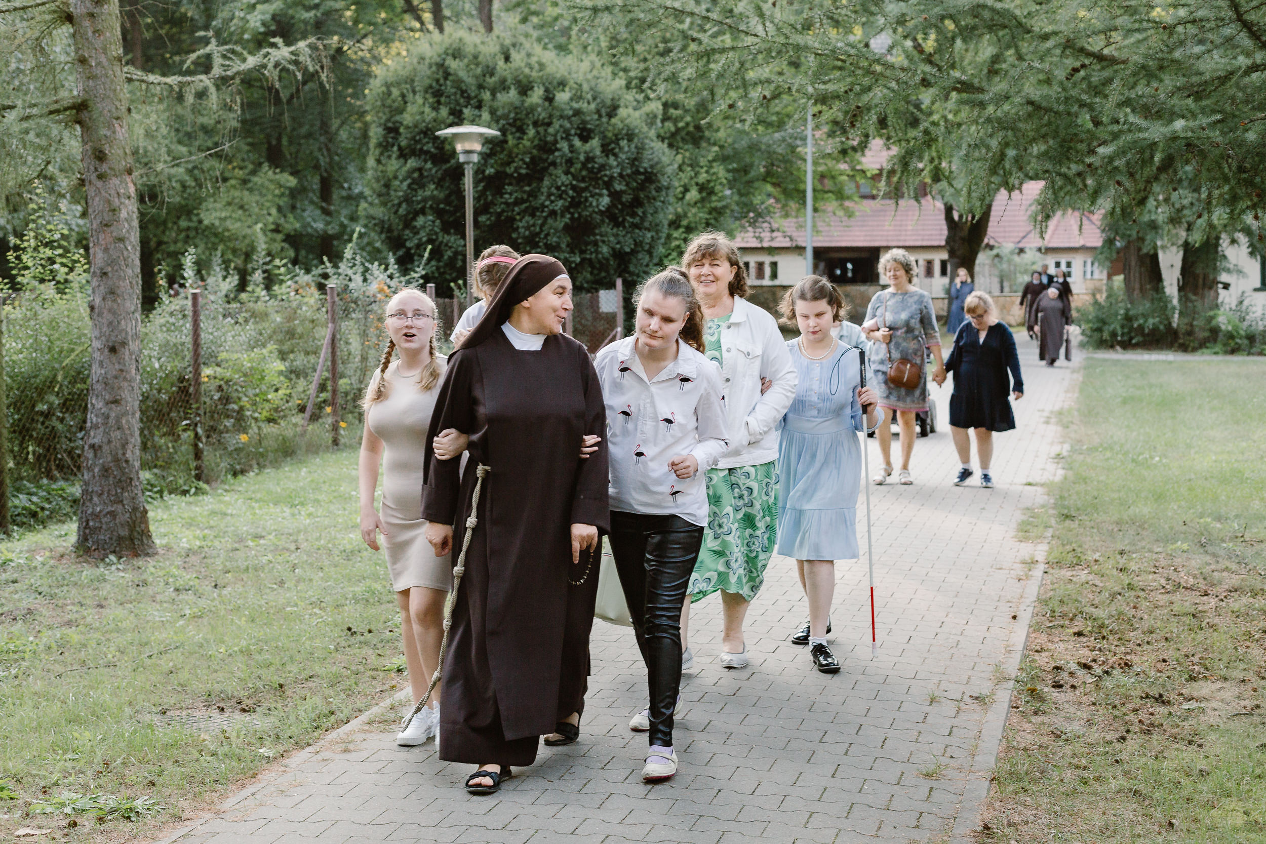 Siostra z dziewczętami idzie pod rękę w kierunku Internatu.