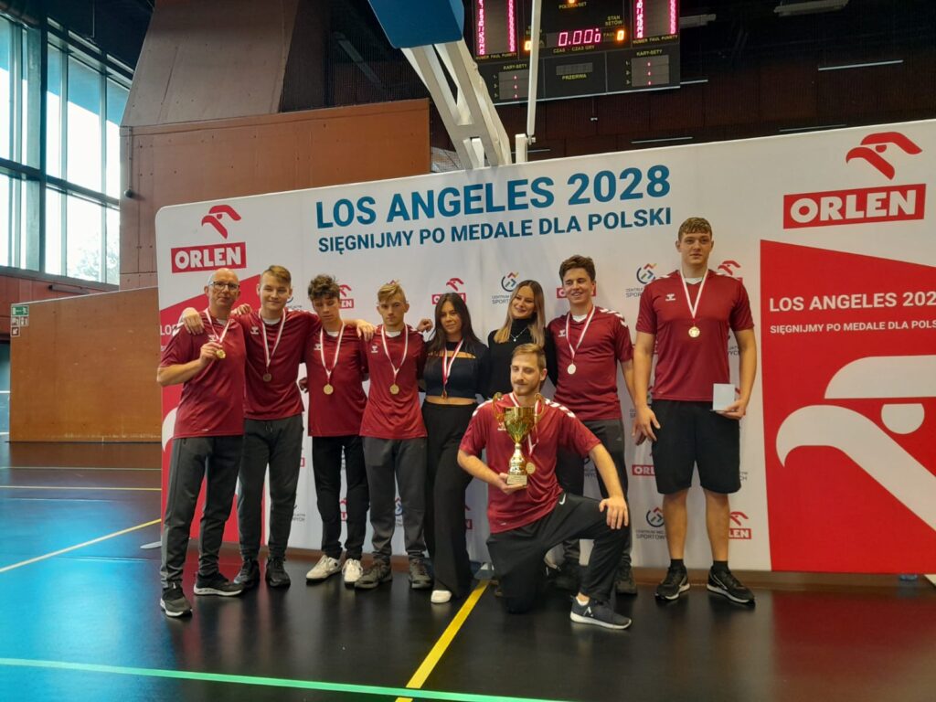 Wspólne zdjęcie drużyny z pucharem i medalami.