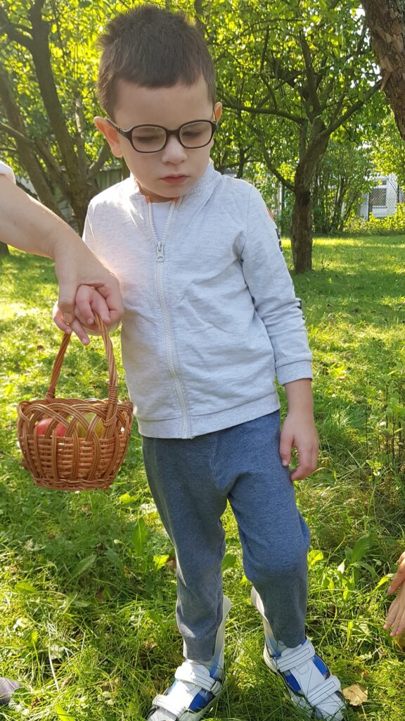 Chłopiec z koszykiem w sadzie.