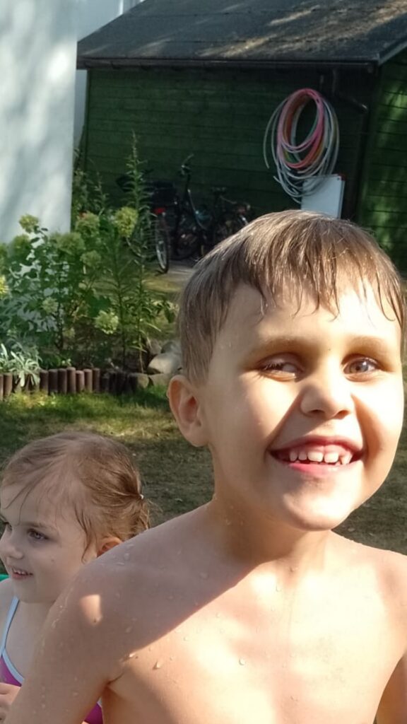 Roześmiany chłopiec po wyjściu z basenika z wodą.