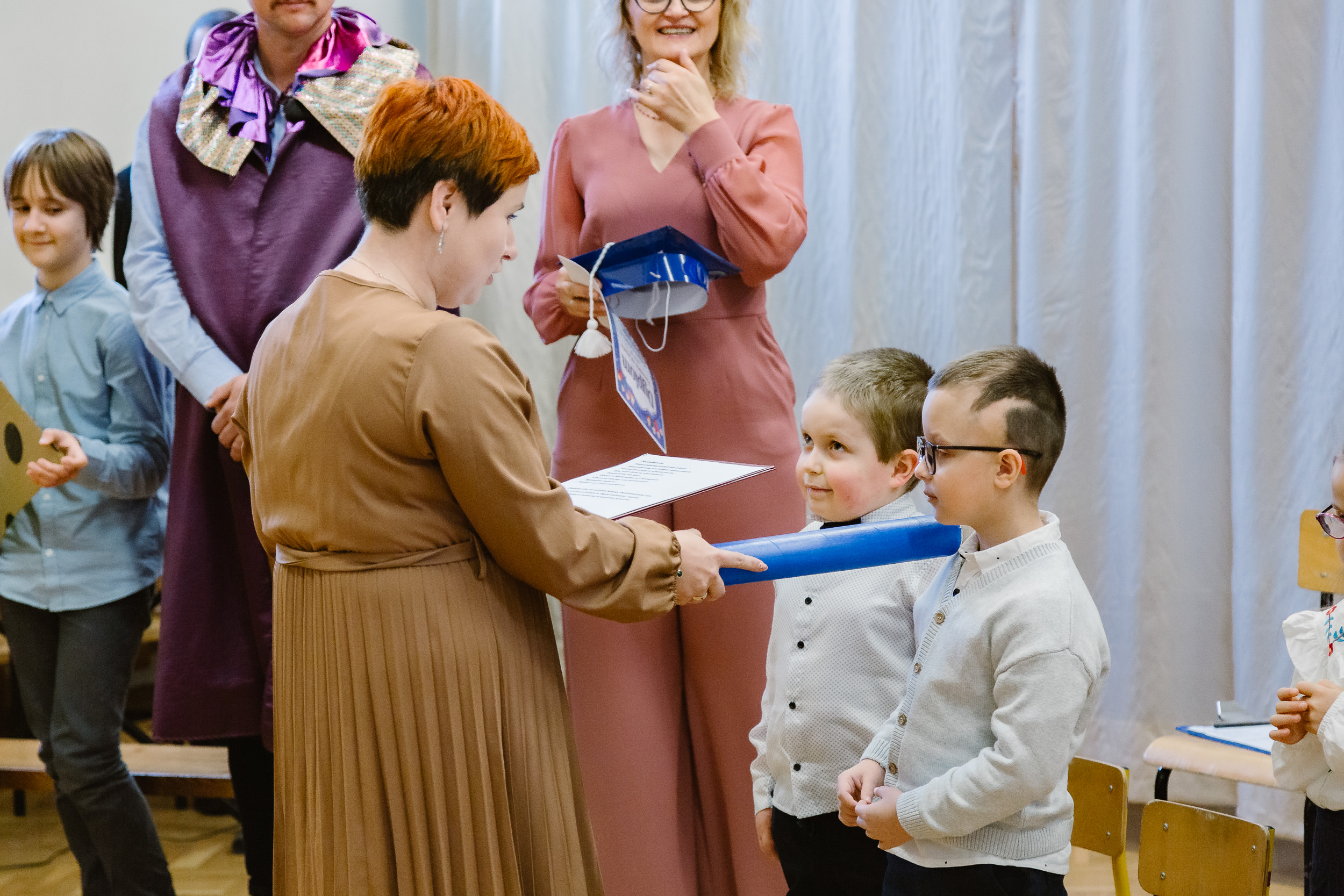 Pani dyrektor dotyka ołówkiem ramienia jednego z uczniów.