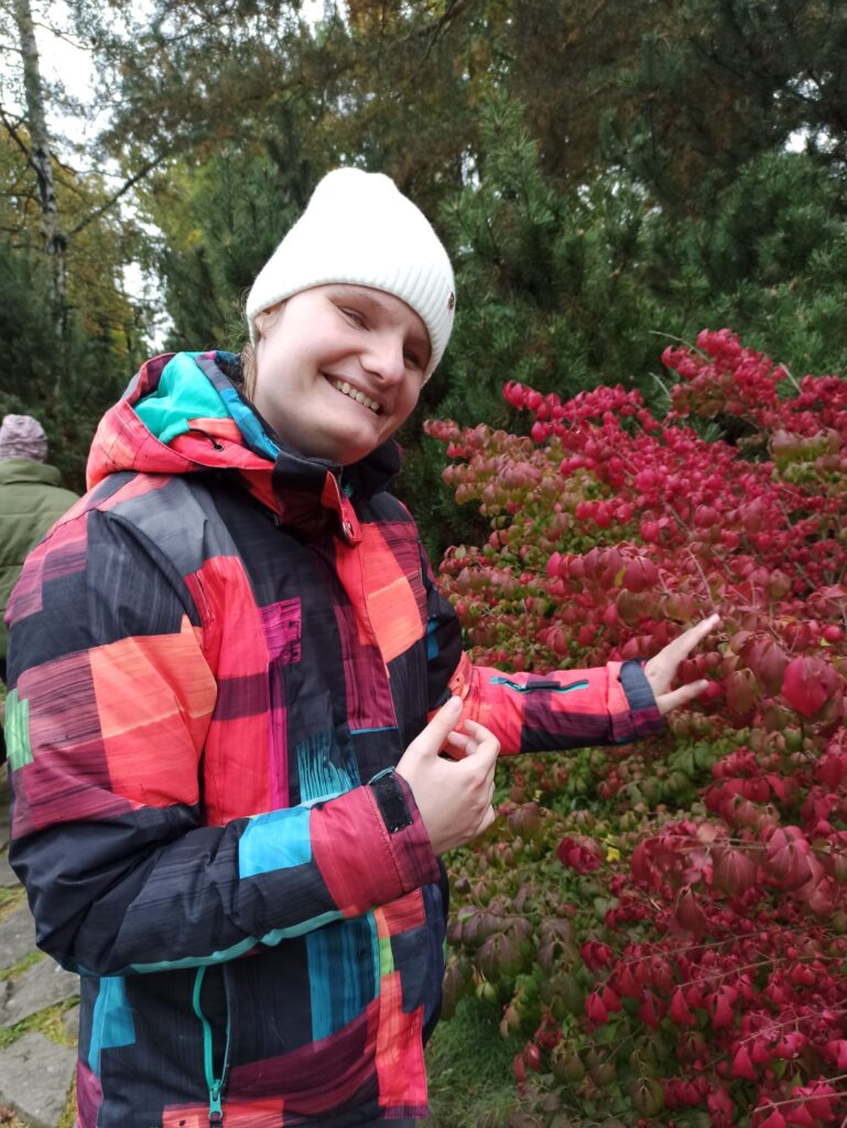 Uśmiechnięta Sandra przy krzewie w parku