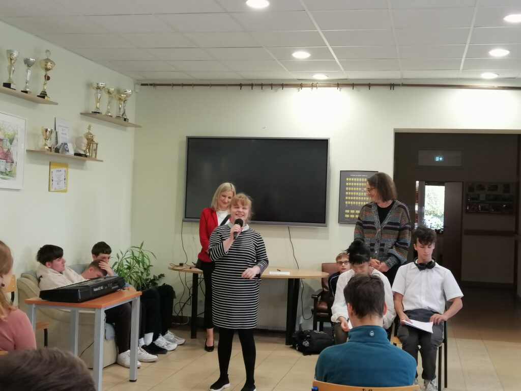 Uczennica klasy pierwszej liceum na korytarzu w szkole średniej opowiada o sobie. Wszyscy uważnie słuchają opowiadań i wierszy.