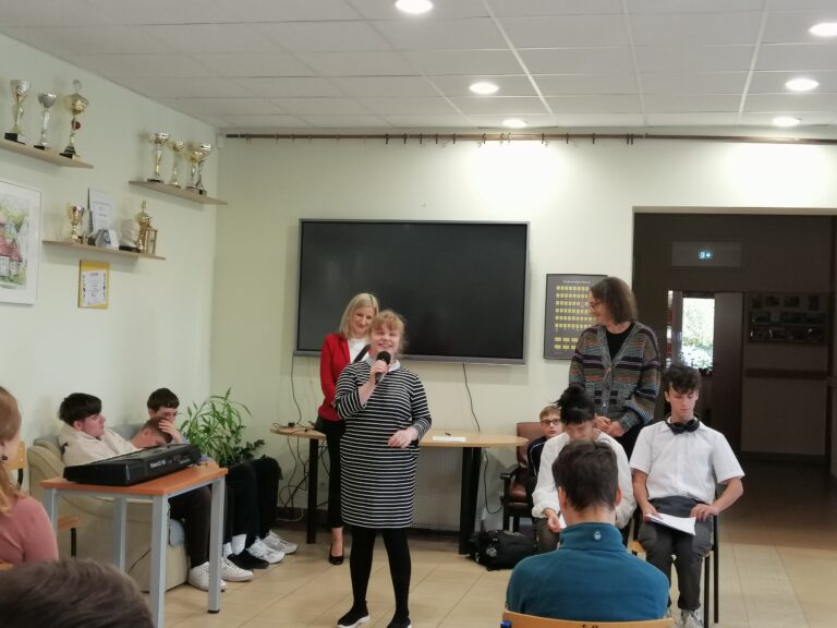 Uczennica klasy pierwszej liceum na korytarzu w szkole średniej opowiada o sobie. Wszyscy uważnie słuchają opowiadań i wierszy.