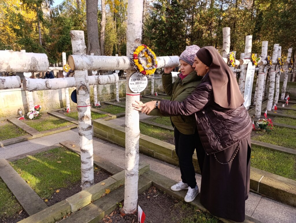 Konstancja bada dotykiem krzyż poległego Harcerza