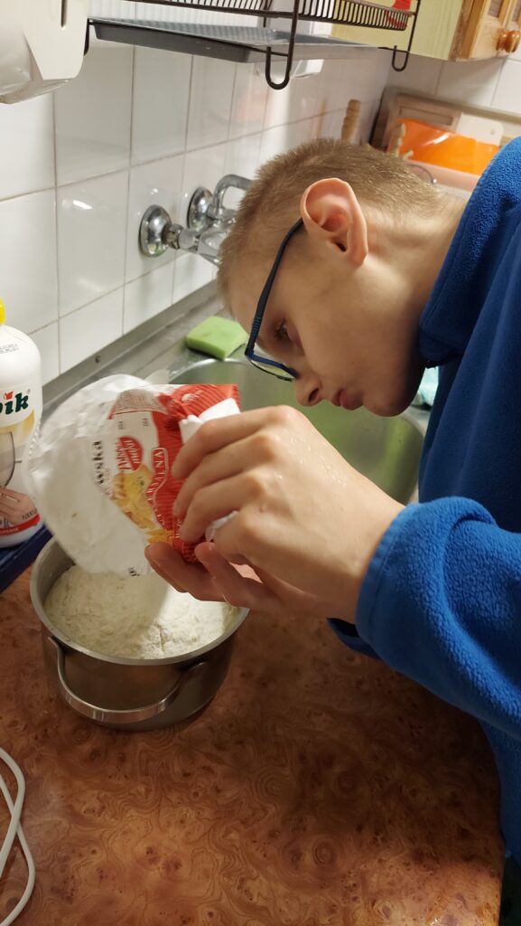 chłopiec wsypuje mąkę do garnka