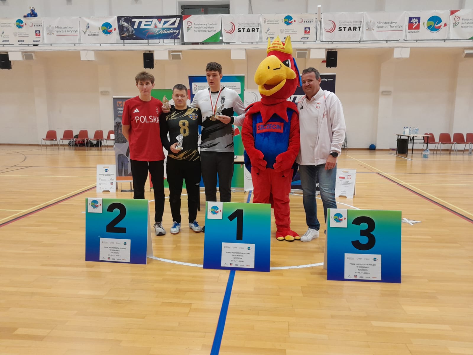 Chłopcy z maskotką turnieju pozują przy podium.