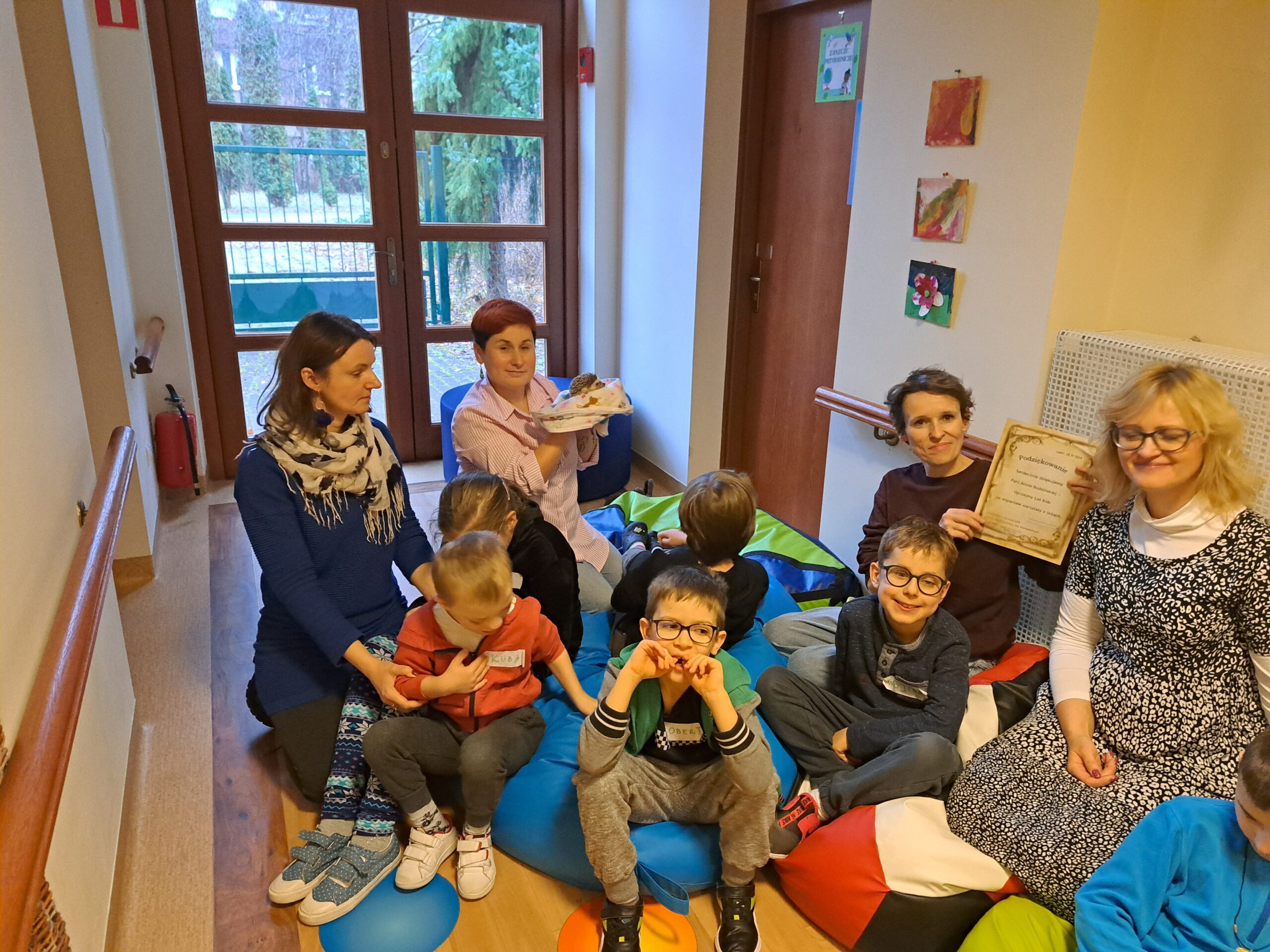 Grupa osób siedząca na pufach