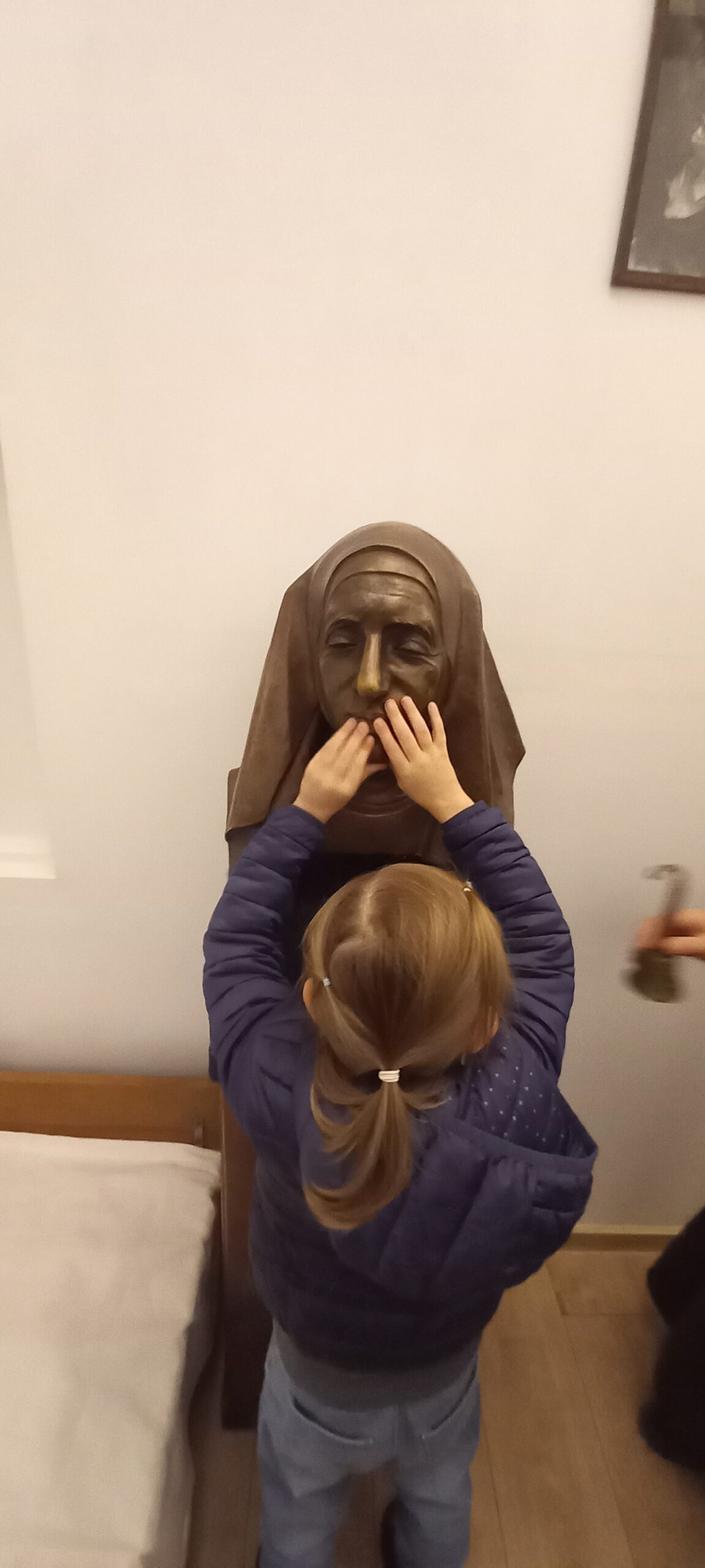 Dziewczynka ogląda dłońmi popiersie Matki Elżbiety Róży Czackiej