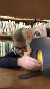 Dziewczynka ogląda książki na regale bibliotecznym.