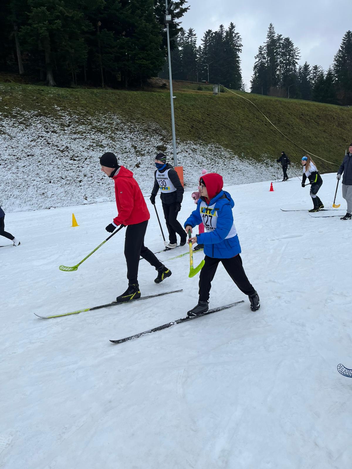 grupa osób z jedną nartą i kijem hokejowym