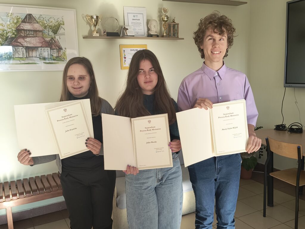 Uczniowie Julia Maciej i Julia prezentują Dyplomy stypendystów.