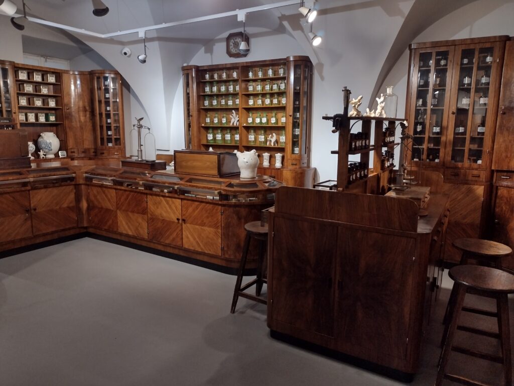Wnętrze muzeum farmacji . Drewniane biurko oraz szafki z lekarstwami.