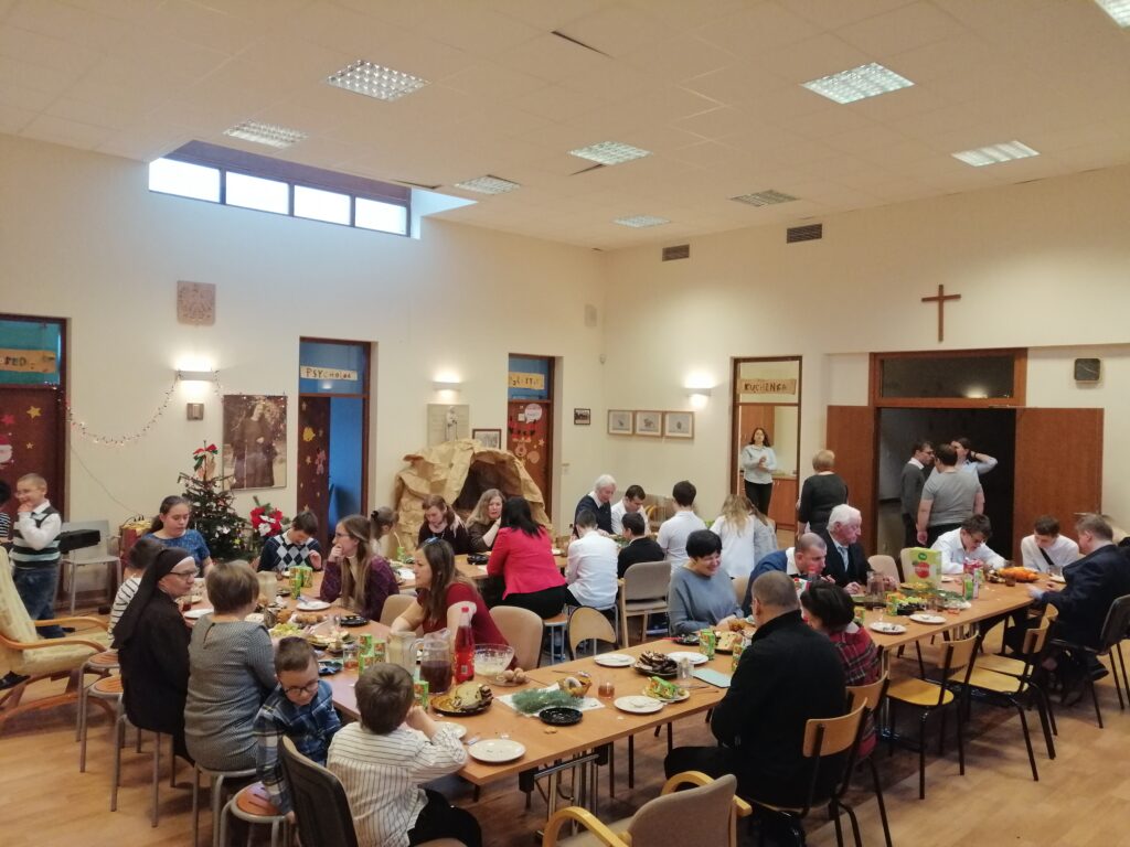 Uczestnicy wigilii rozmawiają i spożywają świąteczne potrawy. 