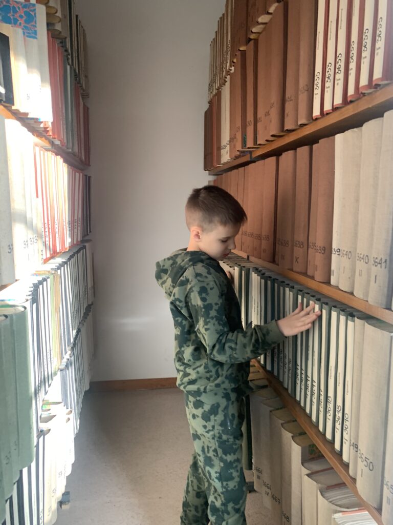 Chłopiec ogląda regał z książkami brajlowskimi