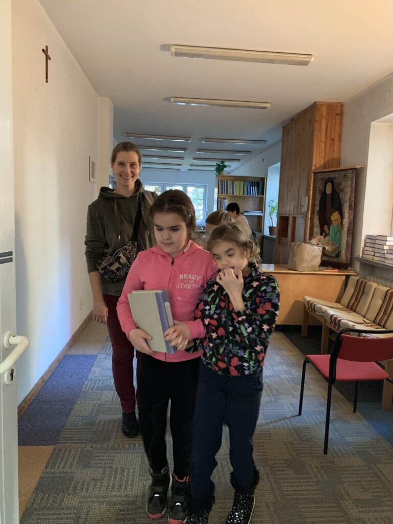 Dwie dziewczynki i nauczycielka wychodzą z biblioteki brajlowskiej