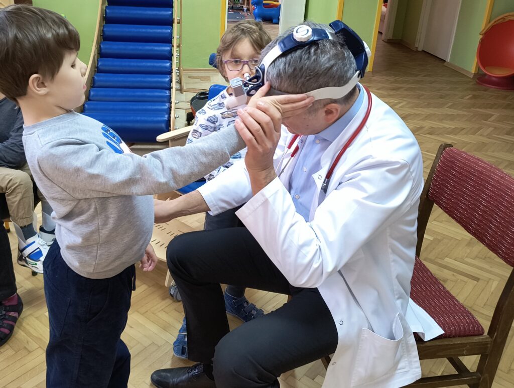 Chłopiec ogląda latarkę na głowie lekarza.