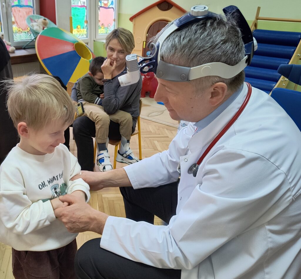 Chłopiec  stoi obok pana doktora.