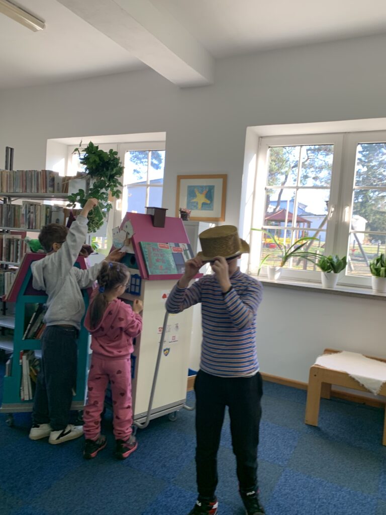 Dzieci oglądają bibliobus, chłopiec ma na głowie kapelusz magika