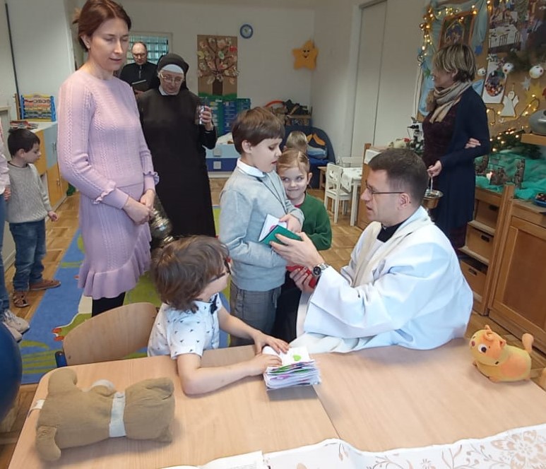 Dzieci z grupy Zuchów pokazują księdzu swoje notesiki
