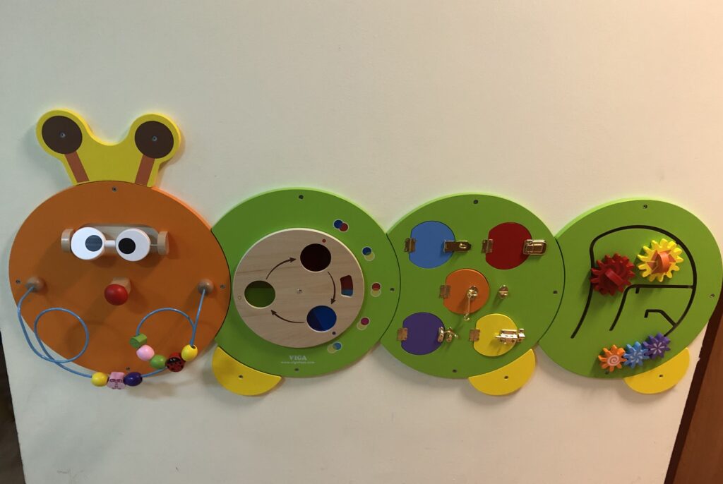 Sensoryczno-manualny panel ścienny dla dzieci w kształcie gąsienicy. 