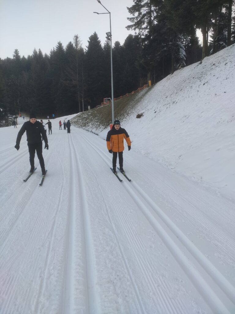 grupa osób jedzie na nartach biegowych