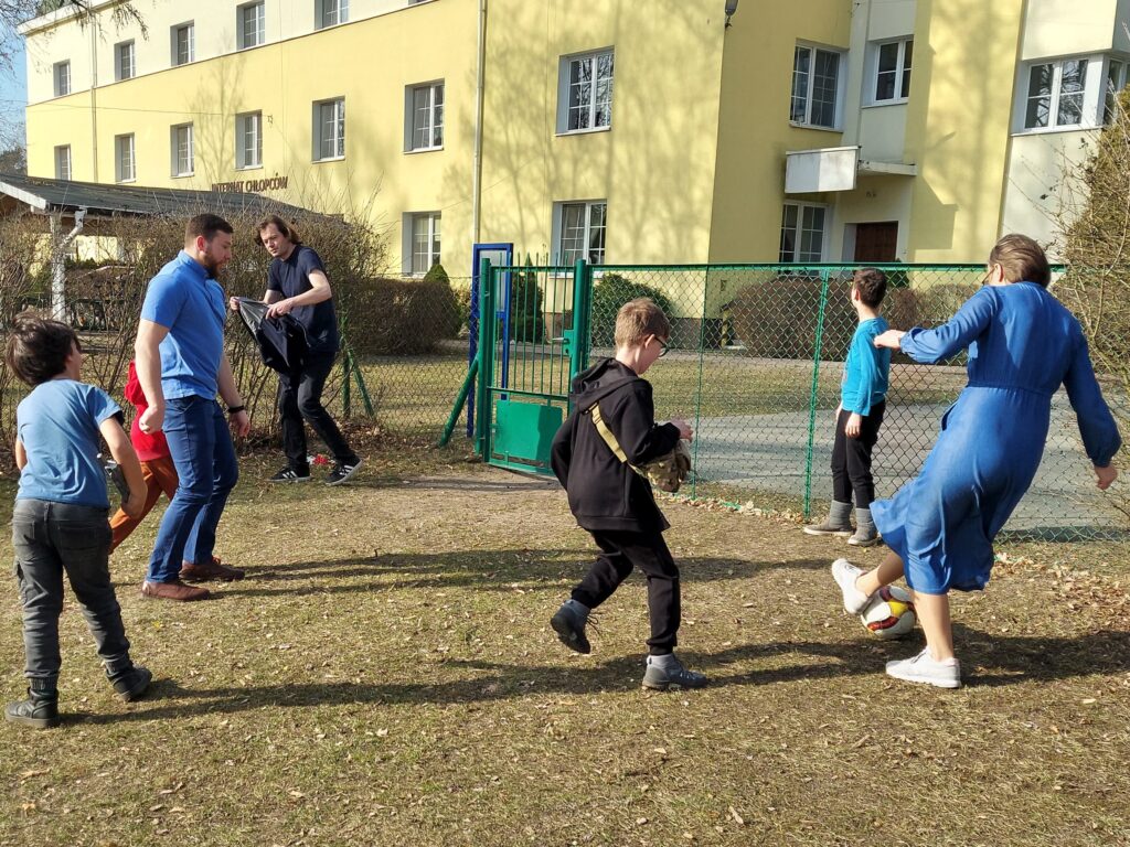 Chłopcy, wychowawcy i pani od orientacji grają w piłkę nożną.