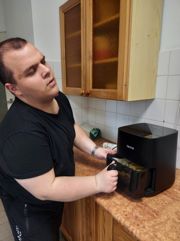 Bartek wkłada ziemniaki do air fryera.