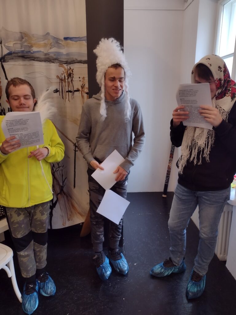 Trzech uczniów przebranych do sceny teatralnej czyta teksty miniatury dramatycznej. 