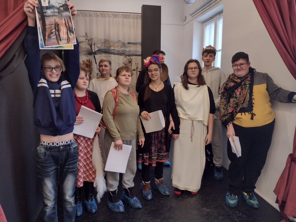 Uczniowie przebrani w stroje do miniatury dramatycznej. Stojąc obok siebie trzymają w dłoniach teksty.