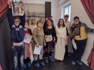 Uczniowie przebrani w stroje do miniatury dramatycznej. Stojąc obok siebie trzymają w dłoniach teksty.
