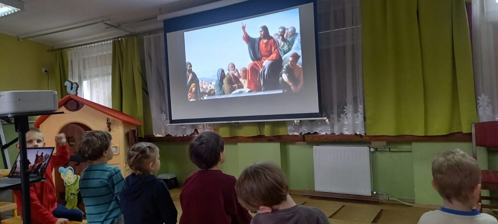 Dzieci siedzące przed ekranem . Na ekranie film religijny.
