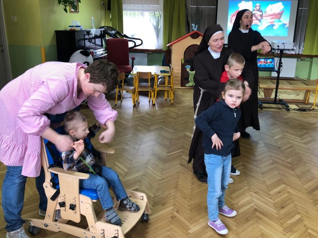 Siostry i pani tańczą z dziećmi.