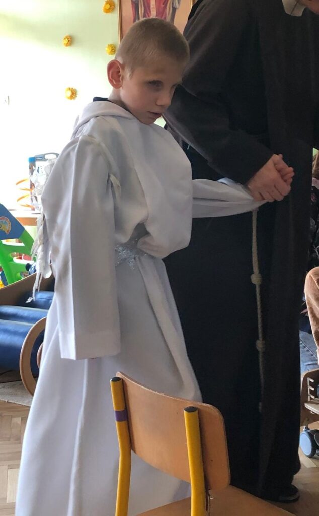 Chłopiec w stroju anioła trzyma za rękę Siostrę.