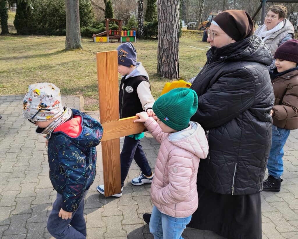 Siostra z trójką dzieci niosą krzyż.