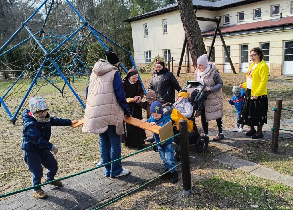Przedszkolaki z Paniami niosą krzyż.