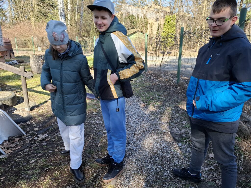 Dwóch uczniów z koleżanką słuchają instrukcji.