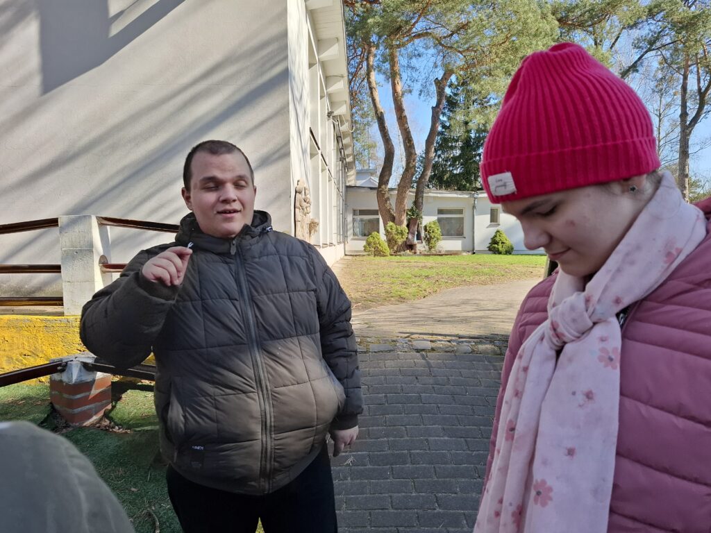 Uczeń stoi obok koleżanki i słuchają poleceń. 