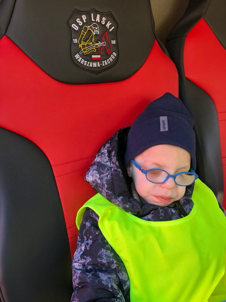 Przedszkolak na fotelu w wozie strażackim.